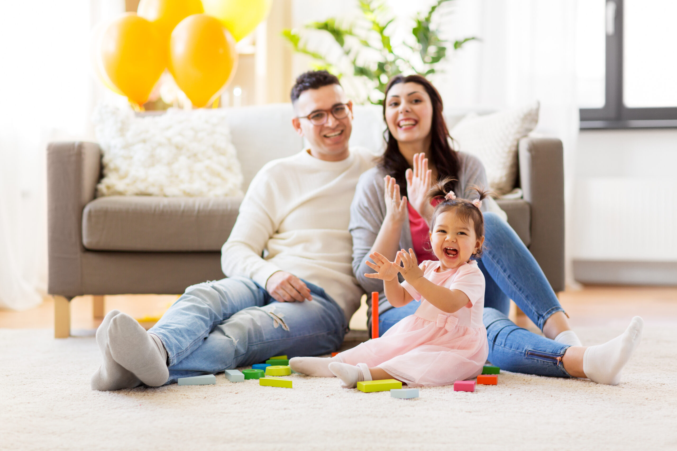 baby girl with parents clapping hands at home